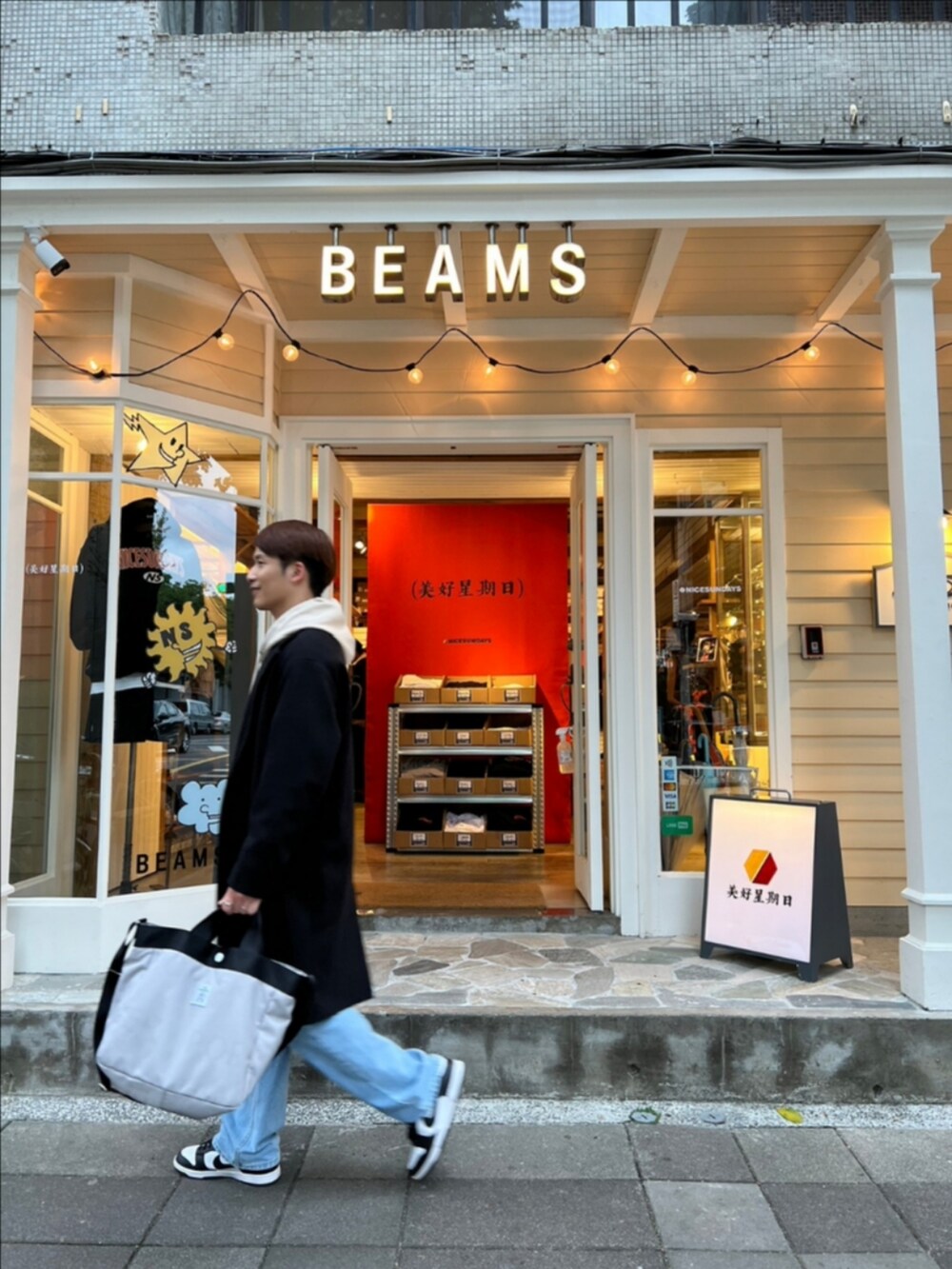 ベージュ系のパーカー、ブラック系のトレンチコート、ブラック系のスニーカーを着用したメンズの春コーディネートの2枚目の写真