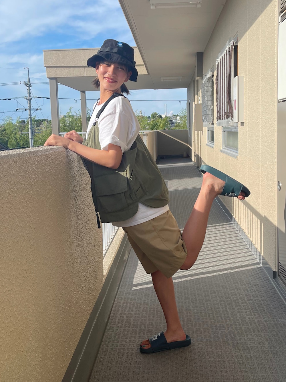 グリーン系のベスト、ベージュ系のパンツ、ブルー系のサンダルを着用したレディースの夏コーディネートの2枚目の写真