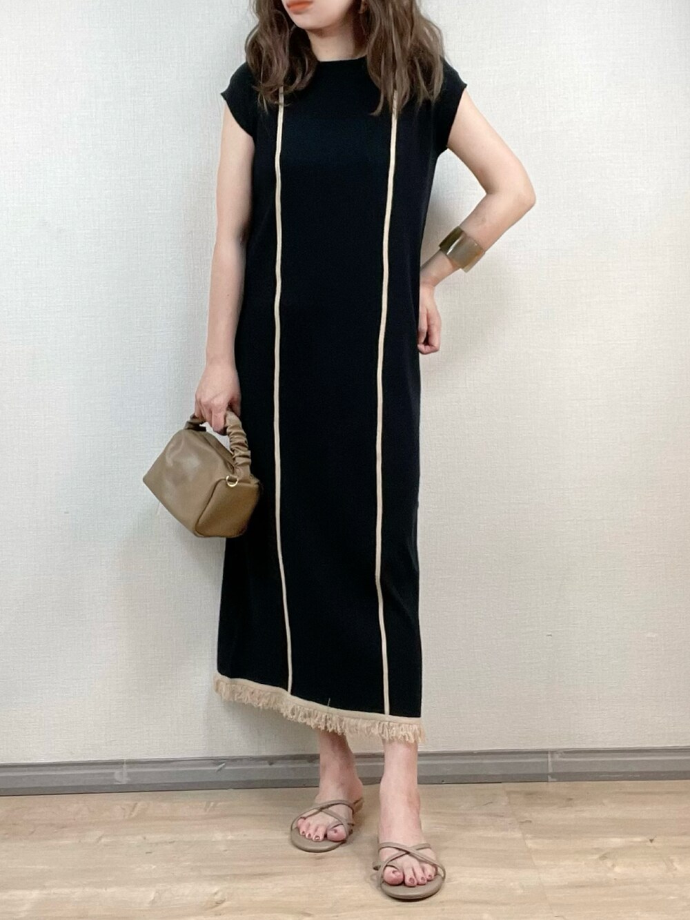 ブラック系のワンピース、ブラウン系のハンドバッグ、ベージュ系のサンダルを着用したレディースの夏コーディネートの2枚目の写真
