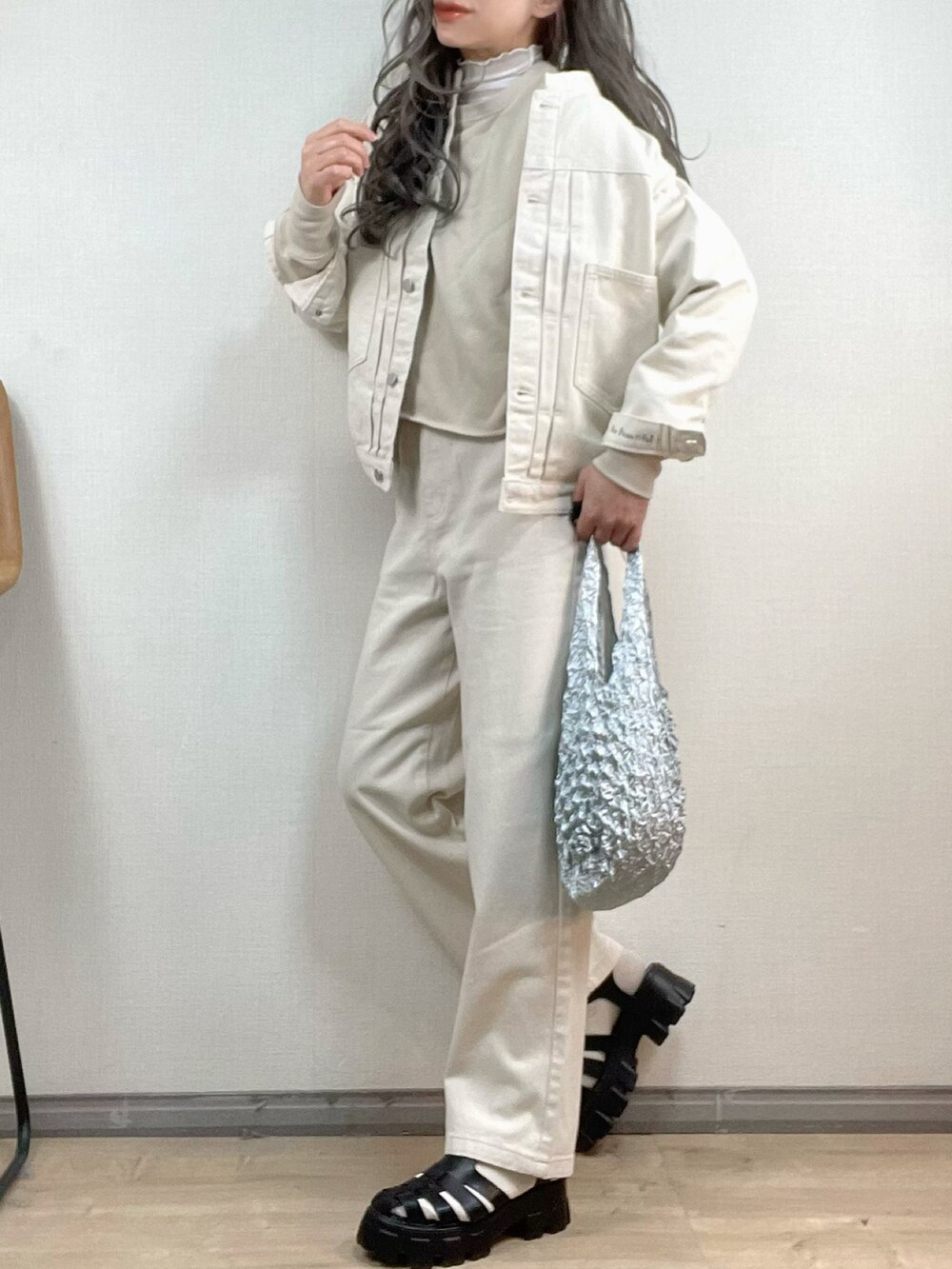 ホワイト系のデニムジャケット、ホワイト系のデニムパンツ、シルバー系のエコバッグ/サブバッグを着用したレディースの冬コーディネートの3枚目の写真