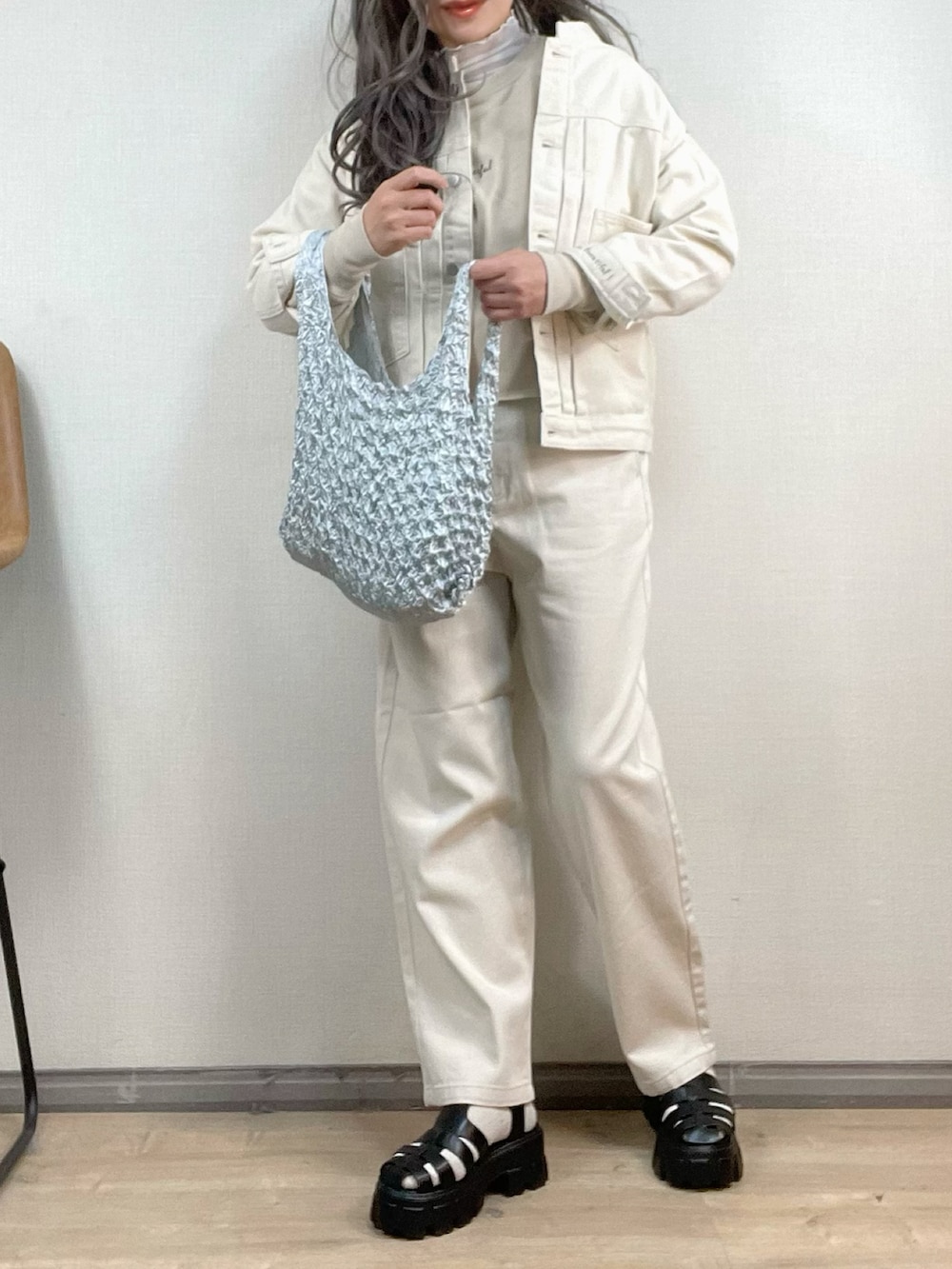 ホワイト系のデニムジャケット、ホワイト系のデニムパンツ、シルバー系のエコバッグ/サブバッグを着用したレディースの冬コーディネートの2枚目の写真