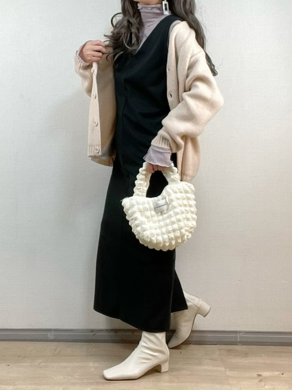 ホワイト系のカーディガン/ボレロ、ブラック系のジャンパースカート、パープル系のTシャツ/カットソーを着用したレディースの冬コーディネートの2枚目の写真