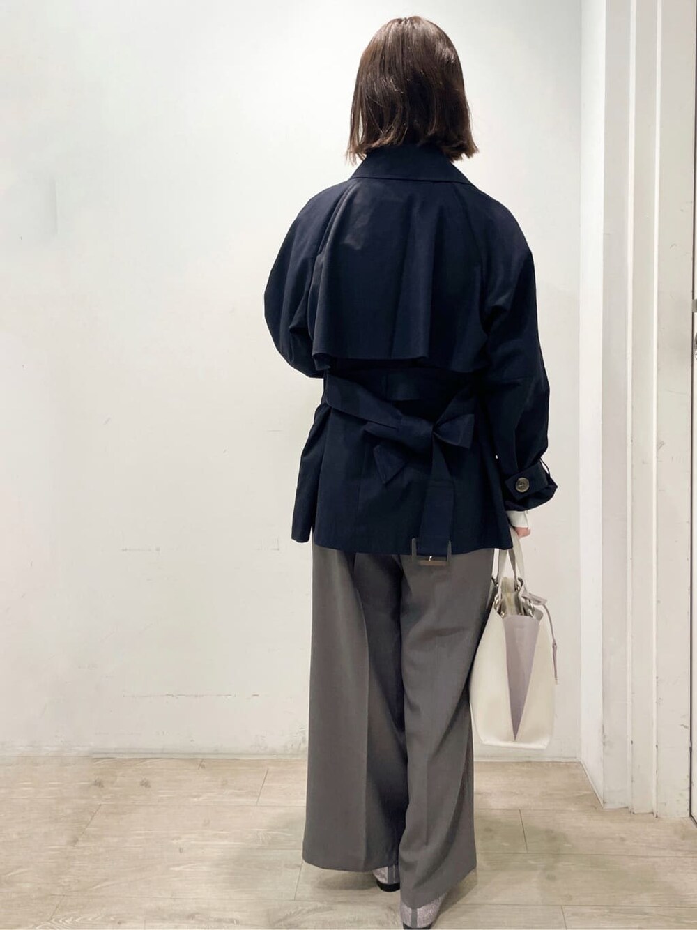 シルバー系のパンプス、ベージュ系のトートバッグ、ブルー系のトレンチコートを着用したレディースの春コーディネートの3枚目の写真
