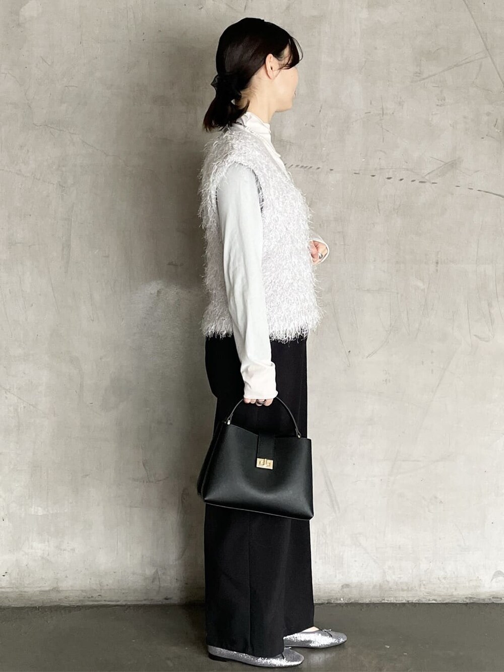 グレー系のニット/セーター、ブラック系のその他パンツ、ブラック系のハンドバッグを着用したレディースの冬コーディネートの3枚目の写真