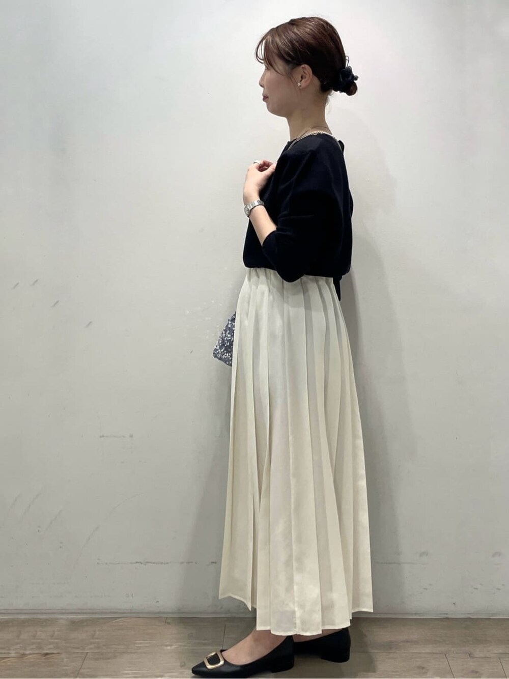 グレー系のショルダーバッグ、ブラック系のパンプス、ホワイト系のスカートを着用したレディースの春コーディネートの3枚目の写真