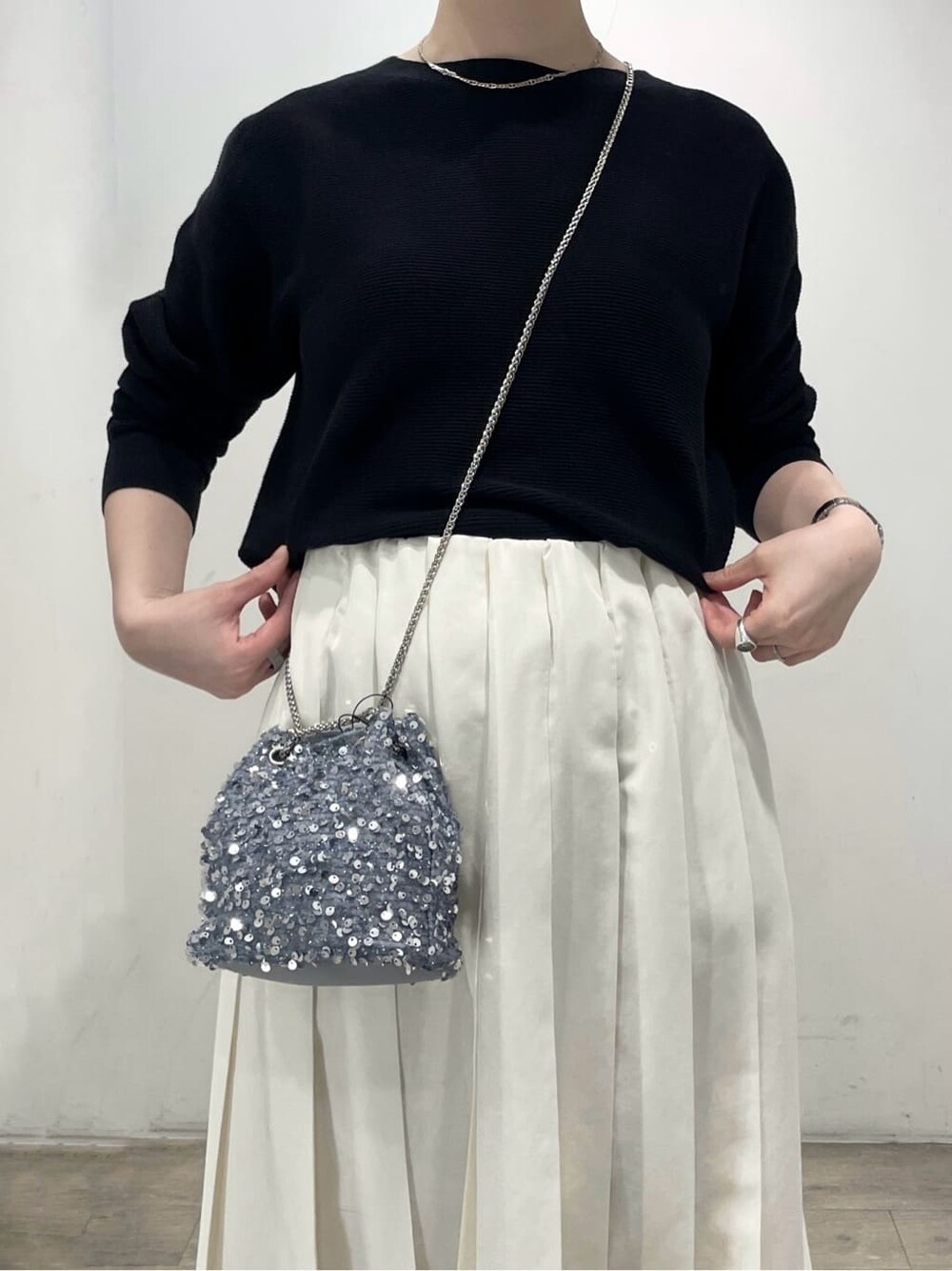 グレー系のショルダーバッグ、ブラック系のパンプス、ホワイト系のスカートを着用したレディースの春コーディネートの6枚目の写真