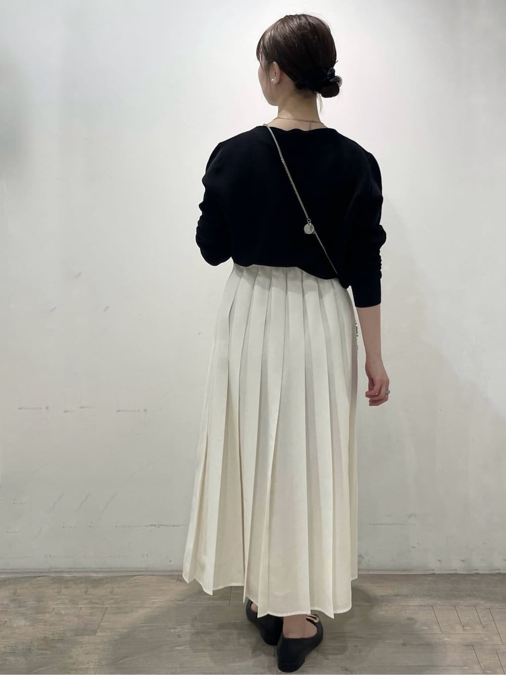 グレー系のショルダーバッグ、ブラック系のパンプス、ホワイト系のスカートを着用したレディースの春コーディネートの4枚目の写真