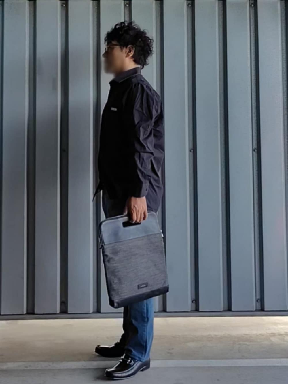 ブラック系のローファー、ブルー系のデニムパンツ、その他のクラッチバッグを着用したメンズの秋コーディネートの3枚目の写真