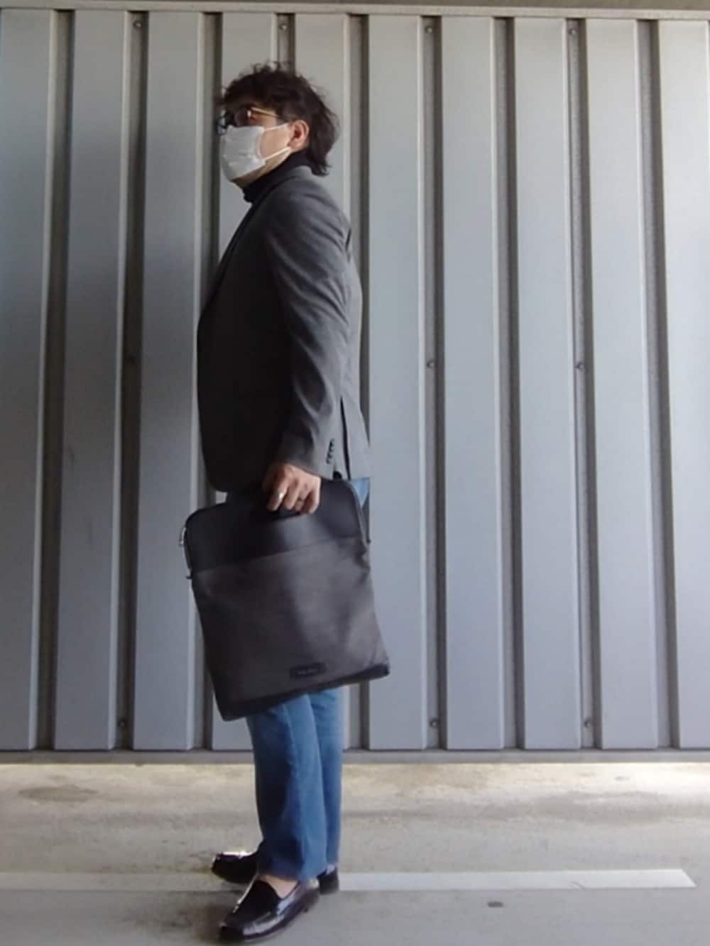 パープル系のローファー、ブルー系のデニムパンツ、その他のクラッチバッグを着用したメンズの春コーディネートの4枚目の写真