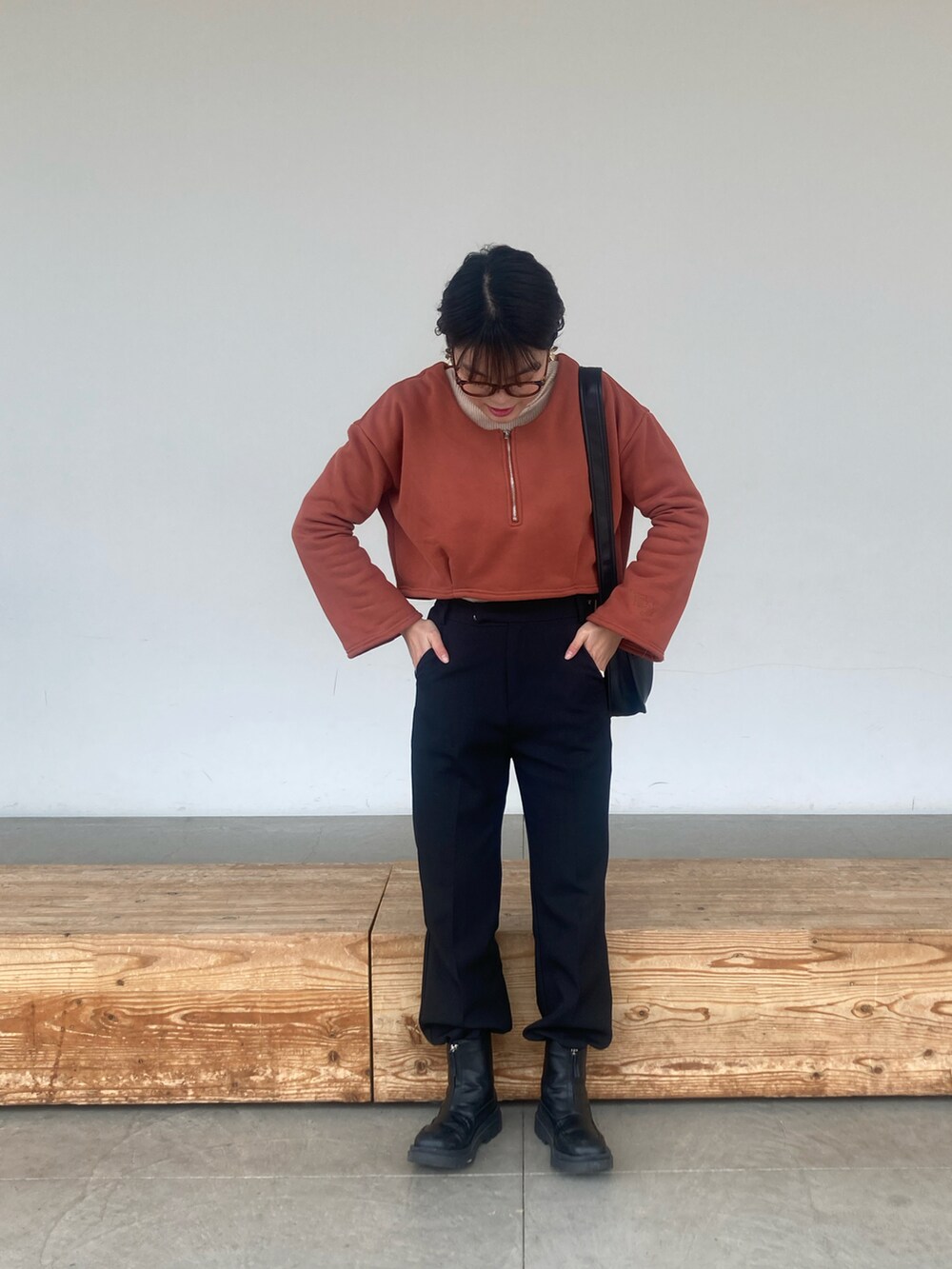 ブラック系のブーツ、ブラック系のその他パンツ、オレンジ系のトップスを着用したレディースの春コーディネートの2枚目の写真