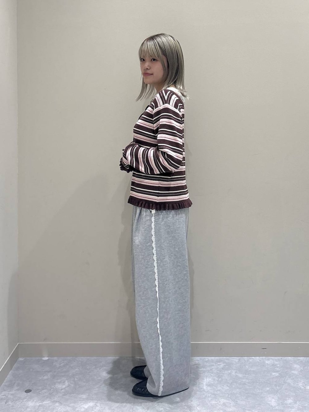 グレー系のスウェットパンツ、ホワイト系のTシャツ/カットソー、ブラウン系のニット/セーターを着用したレディースの冬コーディネートの2枚目の写真