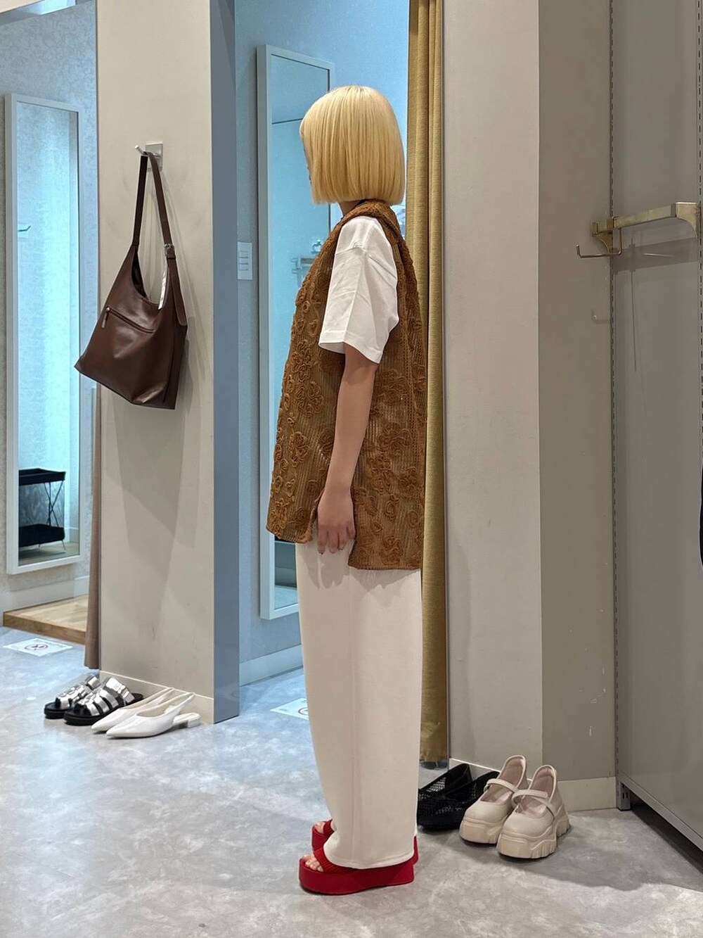 レッド系のサンダル、ホワイト系のTシャツ/カットソー、ブラウン系のベストを着用したレディースの春コーディネートの2枚目の写真
