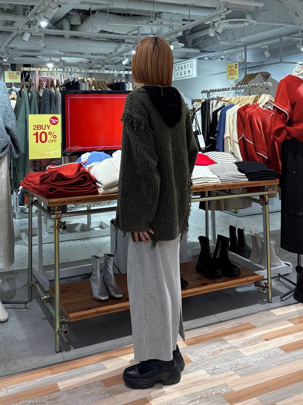 グレー系のスカート、グリーン系のニット/セーター、ブラック系のブーツを着用したレディースの冬コーディネートの2枚目の写真
