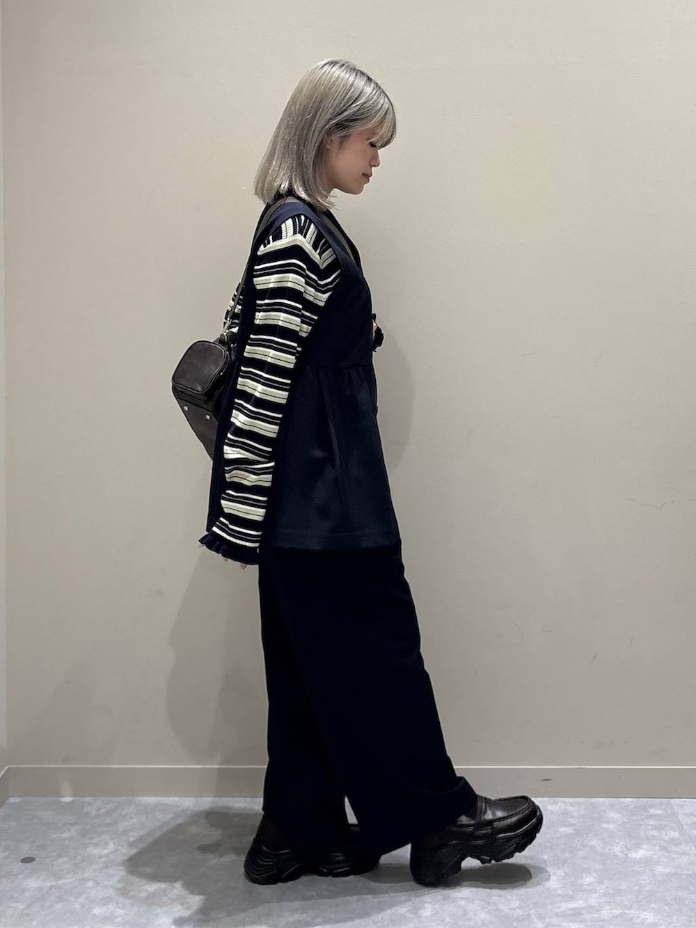 ブルー系のスラックス、ブルー系のベスト、ブラウン系のボストンバッグを着用したレディースの冬コーディネートの4枚目の写真