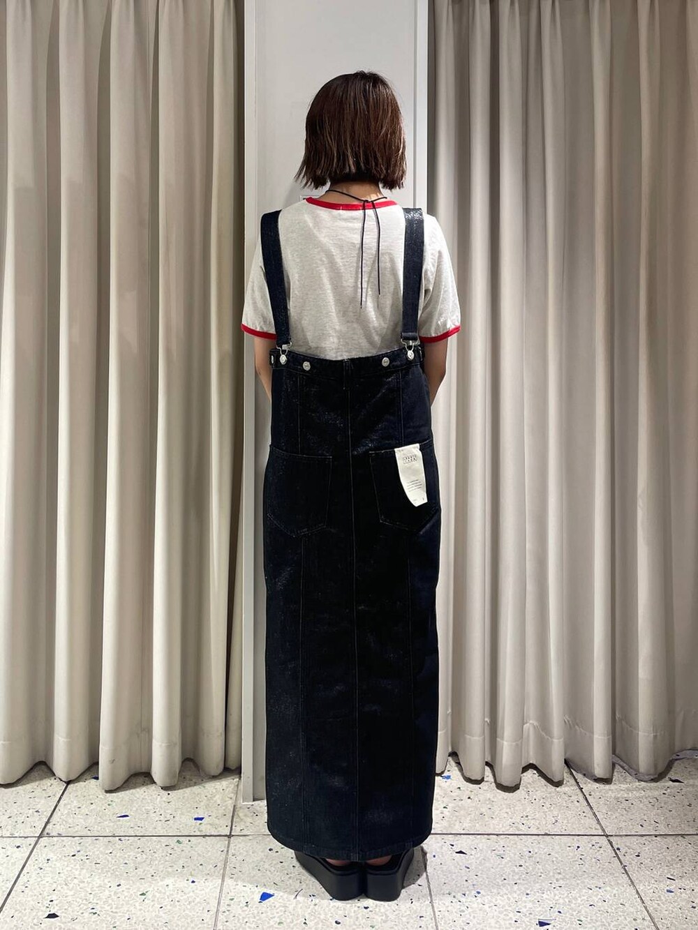 ホワイト系のサンダル、ホワイト系のTシャツ/カットソー、ブラック系のジャンパースカートを着用したレディースの夏コーディネートの3枚目の写真