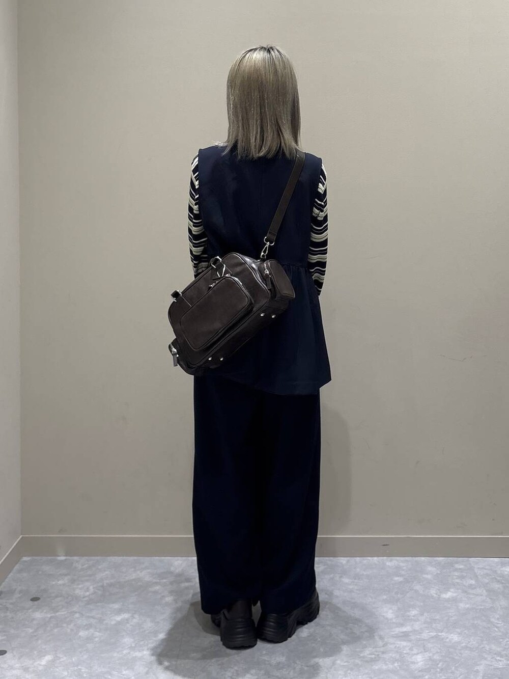 ブルー系のスラックス、ブルー系のベスト、ブラウン系のボストンバッグを着用したレディースの冬コーディネートの3枚目の写真