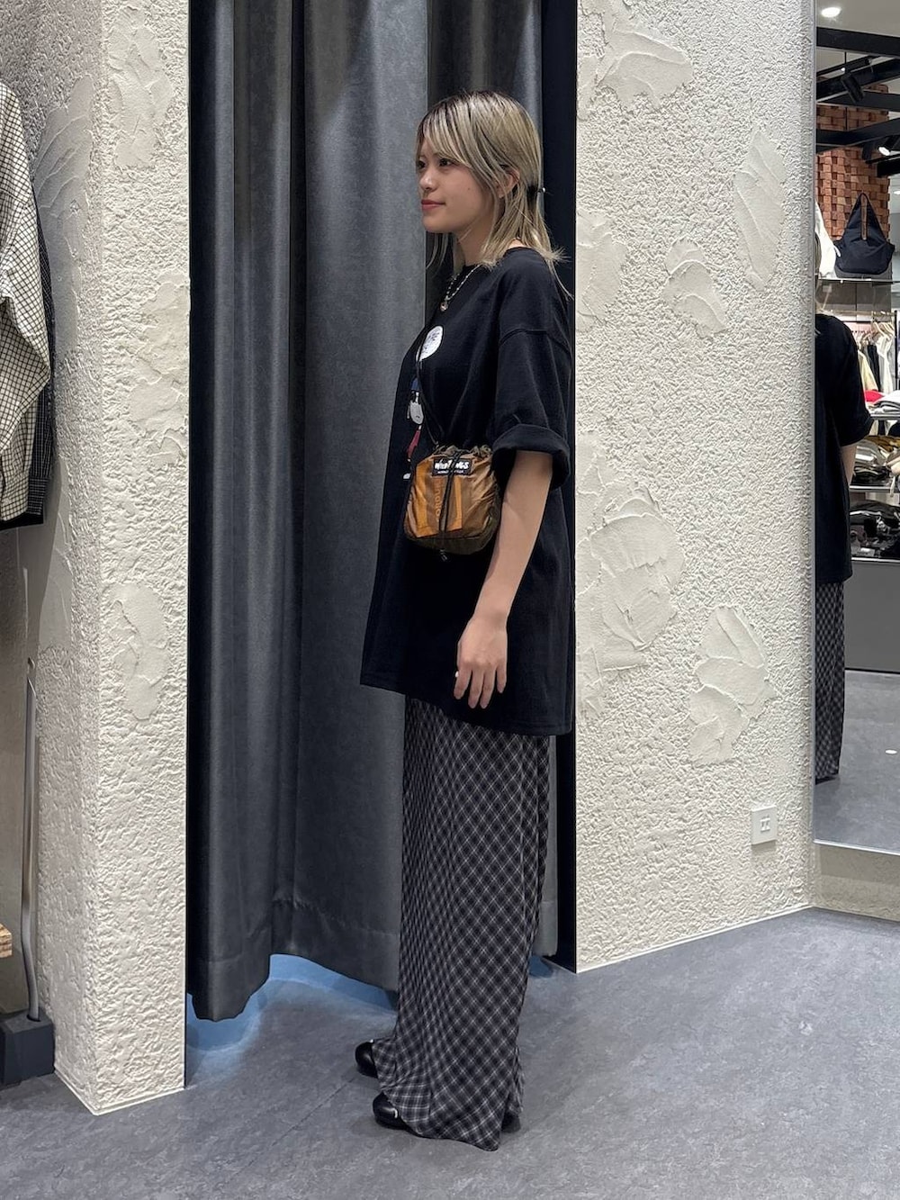 ブラウン系のショルダーバッグ、グレー系のスカート、ブラック系のTシャツ/カットソーを着用したレディースの春コーディネートの2枚目の写真