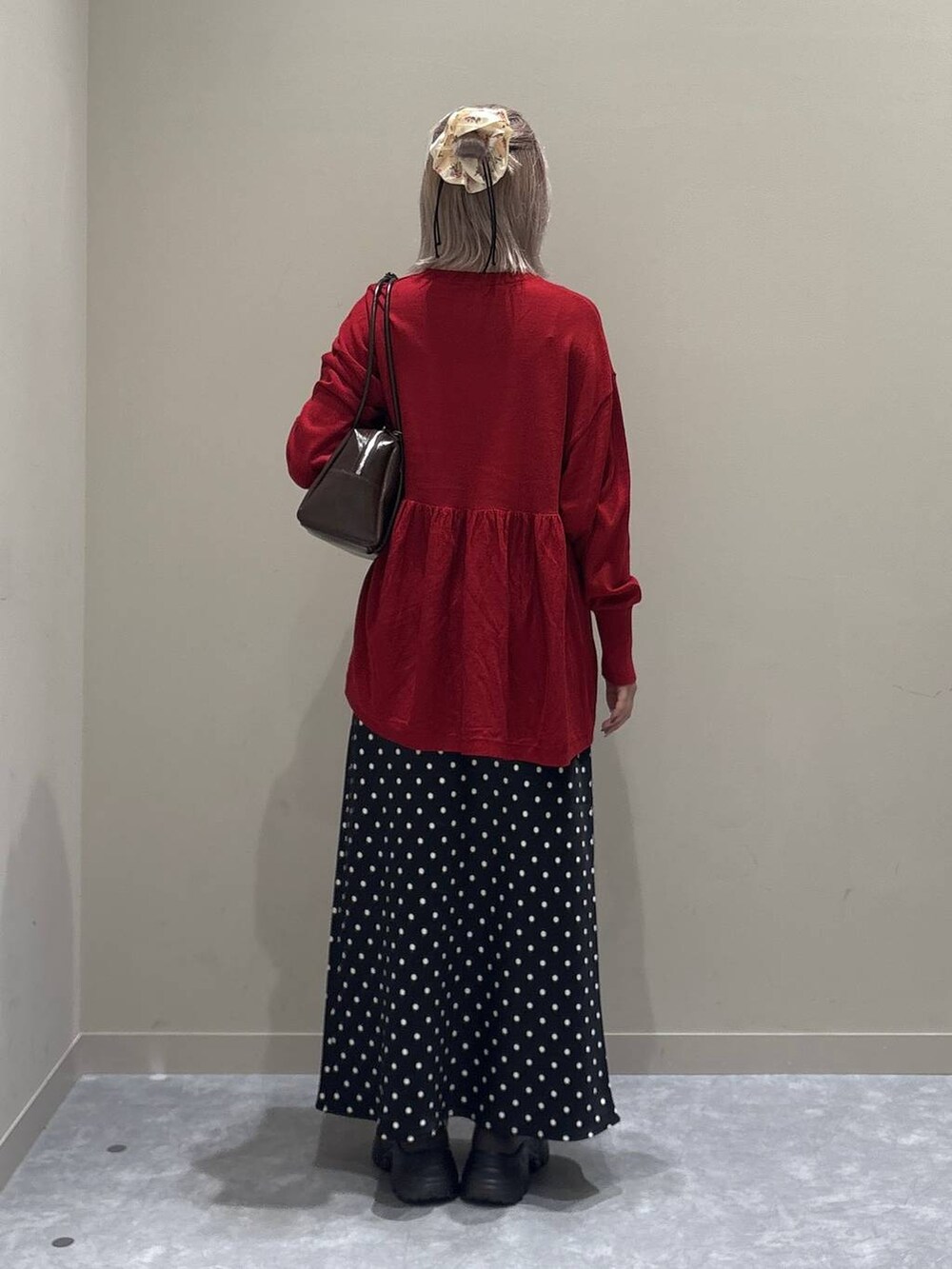 ブラック系のスカート、レッド系のニット/セーター、レッド系のボストンバッグを着用したレディースの秋コーディネートの3枚目の写真