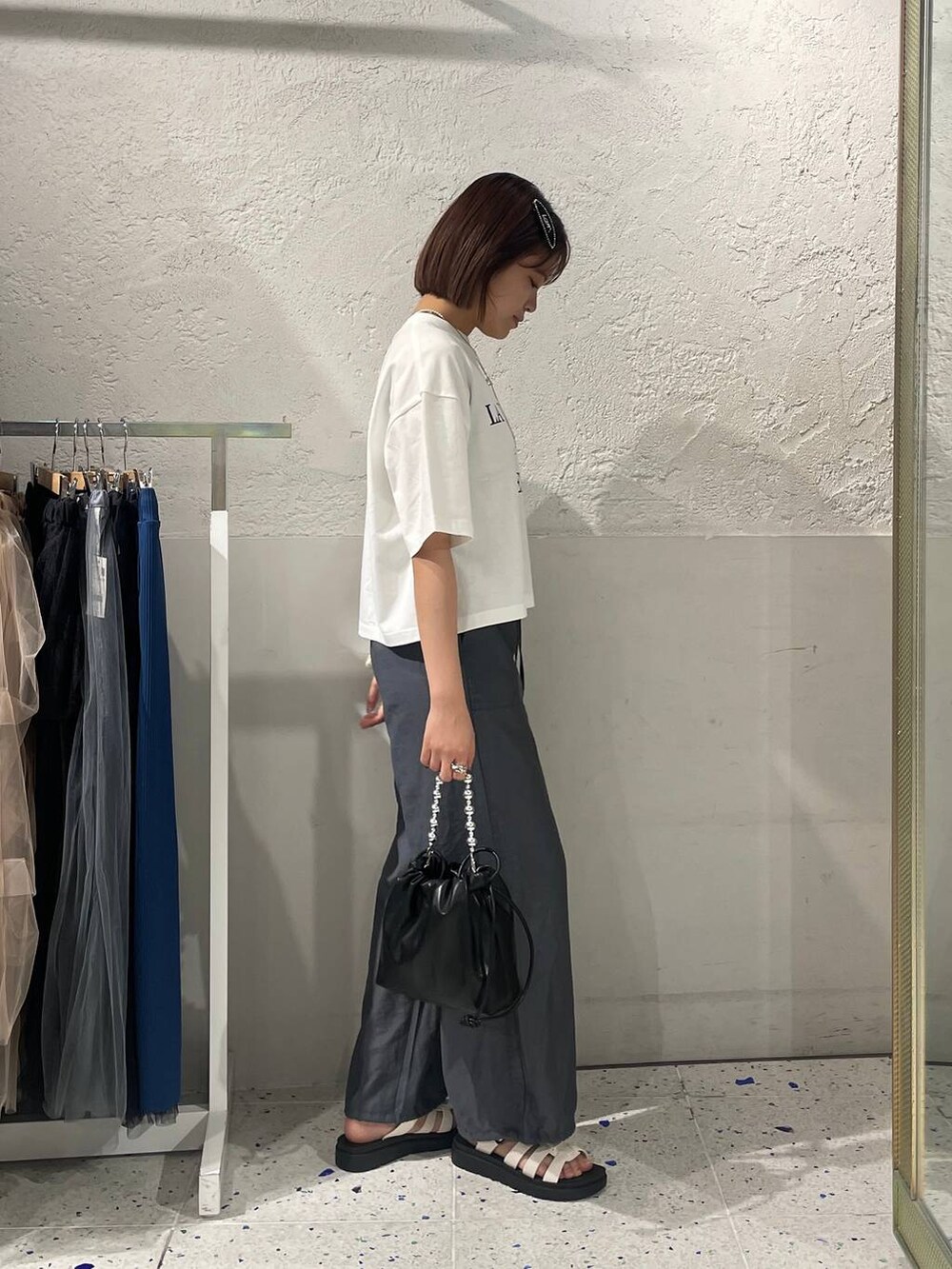 グレー系のセットアップ、ホワイト系のスニーカー、ブラック系のショルダーバッグを着用したレディースの夏コーディネートの3枚目の写真