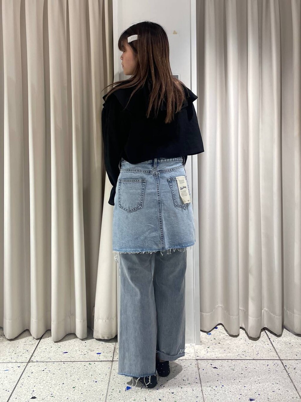 グレー系のニット/セーター、ブラック系のシャツ/ブラウス、ブルー系のデニムパンツを着用したレディースの冬コーディネートの2枚目の写真