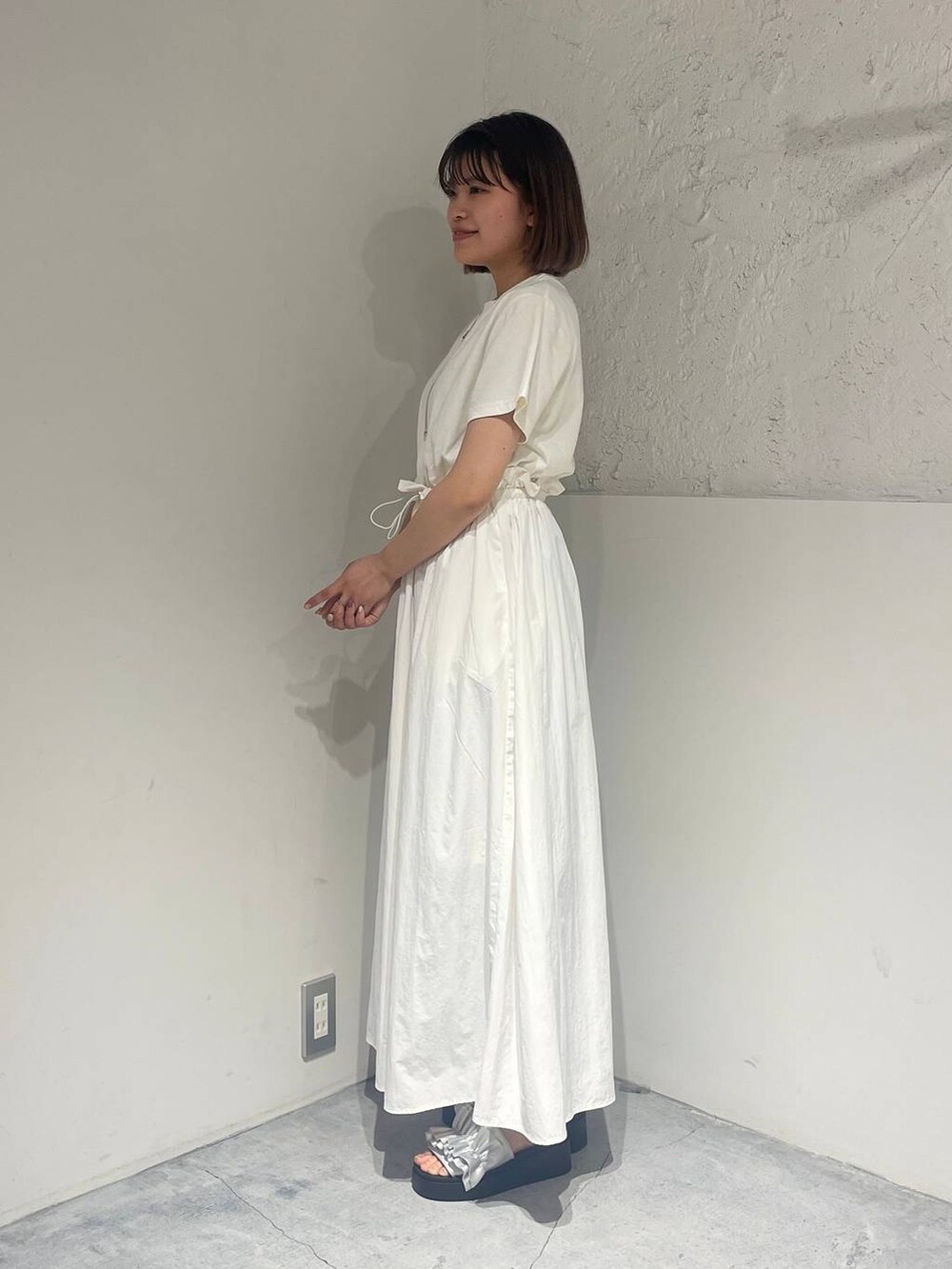 シルバー系のサンダル、ホワイト系のワンピース、シルバー系のネックレスを着用したレディースの春コーディネートの2枚目の写真