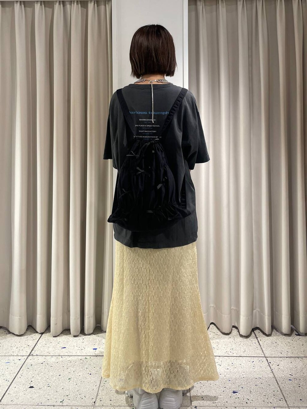 イエロー系のスカート、シルバー系のスニーカー、ブラック系のバックパック/リュックを着用したレディースの夏コーディネートの3枚目の写真