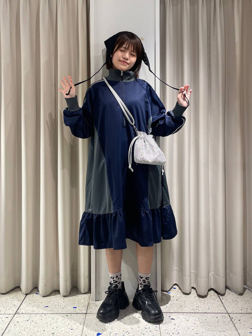 シルバー系のショルダーバッグ、ブラック系のスニーカー、ブルー系のワンピースを着用したレディースの夏コーディネートの4枚目の写真