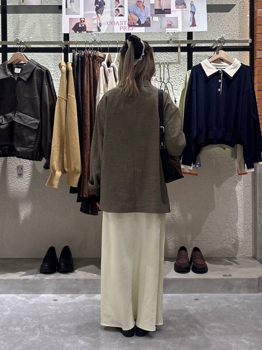 イエロー系のスカート、ブラウン系のテーラードジャケット、ブラック系のローファーを着用したレディースの春コーディネートの3枚目の写真