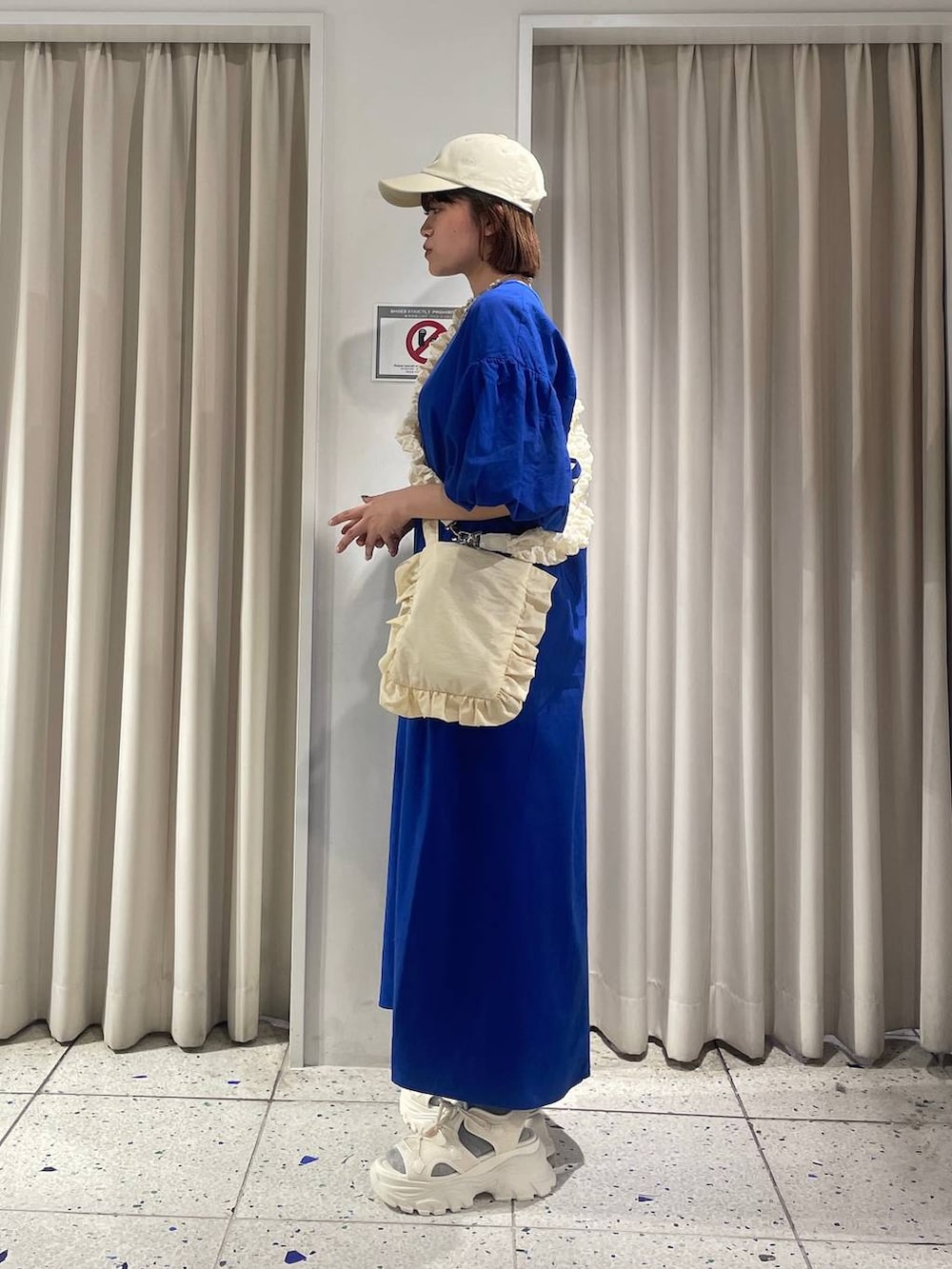 ブルー系のワンピース、ホワイト系のサンダル、ホワイト系のショルダーバッグを着用したレディースの春コーディネートの2枚目の写真