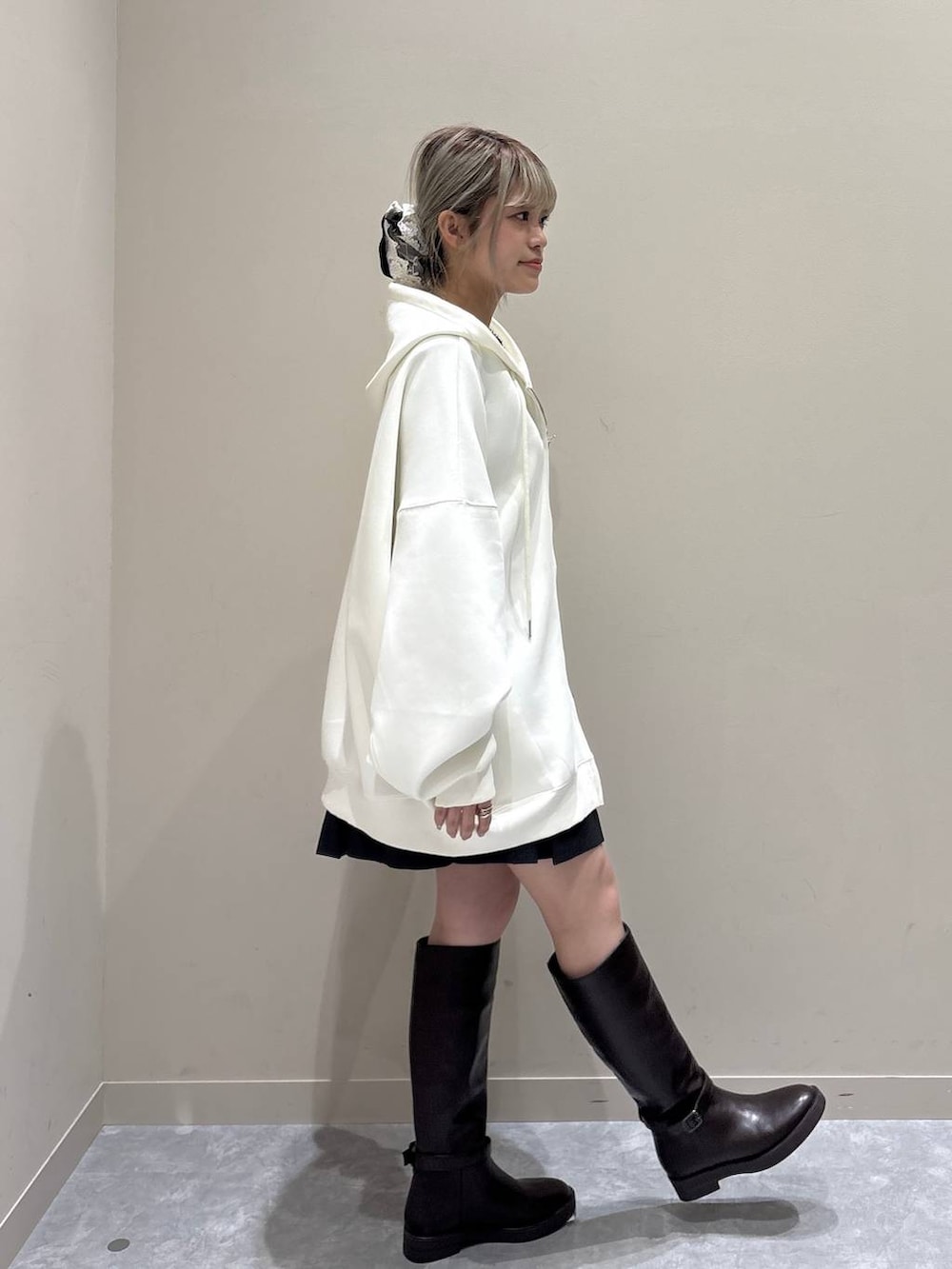 ベージュ系のパーカー、ブラウン系のブーツ、グレー系のスカートを着用したレディースの春コーディネートの4枚目の写真