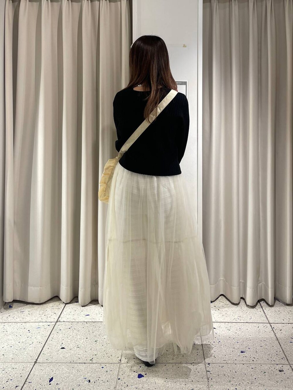 ホワイト系のその他パンツ、ブラック系のカーディガン/ボレロ、ホワイト系のスカートを着用したレディースの春コーディネートの3枚目の写真