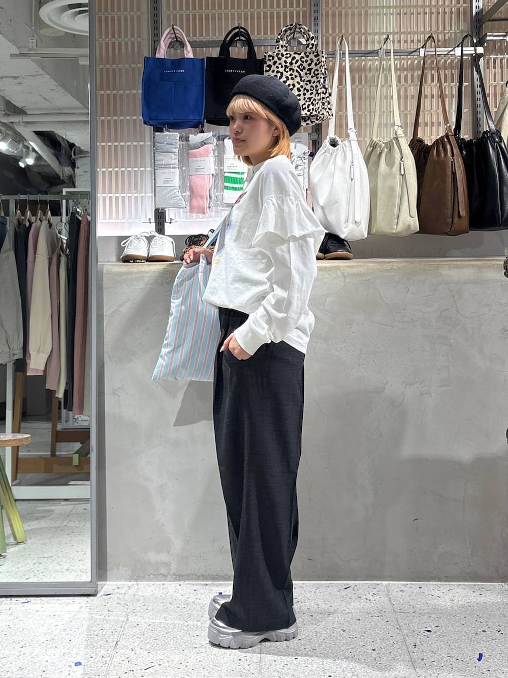 グレー系のスラックス、その他のトートバッグ、ホワイト系のTシャツ/カットソーを着用したレディースの春コーディネートの2枚目の写真