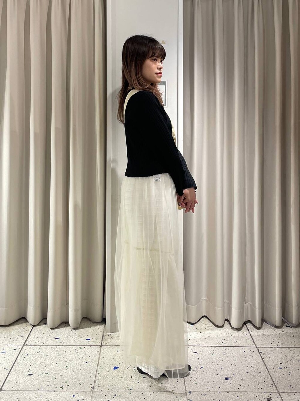 ホワイト系のその他パンツ、ブラック系のカーディガン/ボレロ、ホワイト系のスカートを着用したレディースの春コーディネートの2枚目の写真