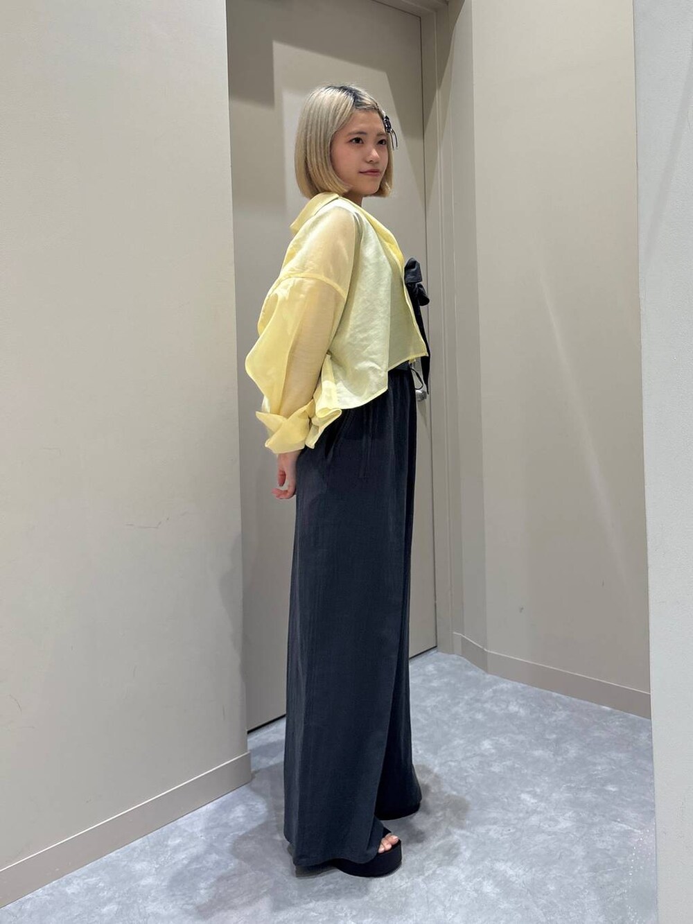 ホワイト系のTシャツ/カットソー、イエロー系のシャツ/ブラウス、ブラック系のサンダルを着用したレディースの春コーディネートの4枚目の写真