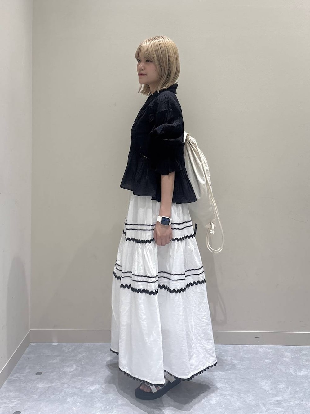 シルバー系のサンダル、ホワイト系のスカート、ブラック系のシャツ/ブラウスを着用したレディースの夏コーディネートの2枚目の写真
