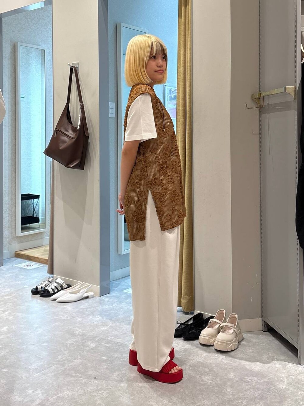 レッド系のサンダル、ホワイト系のTシャツ/カットソー、ブラウン系のベストを着用したレディースの春コーディネートの4枚目の写真