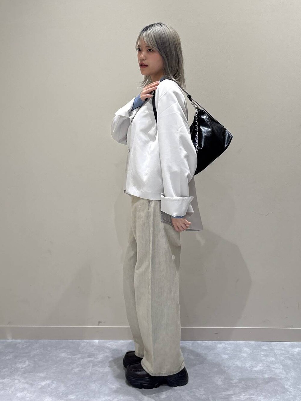 ベージュ系のデニムパンツ、ホワイト系のテーラードジャケット、ブラック系のショルダーバッグを着用したレディースの冬コーディネートの2枚目の写真