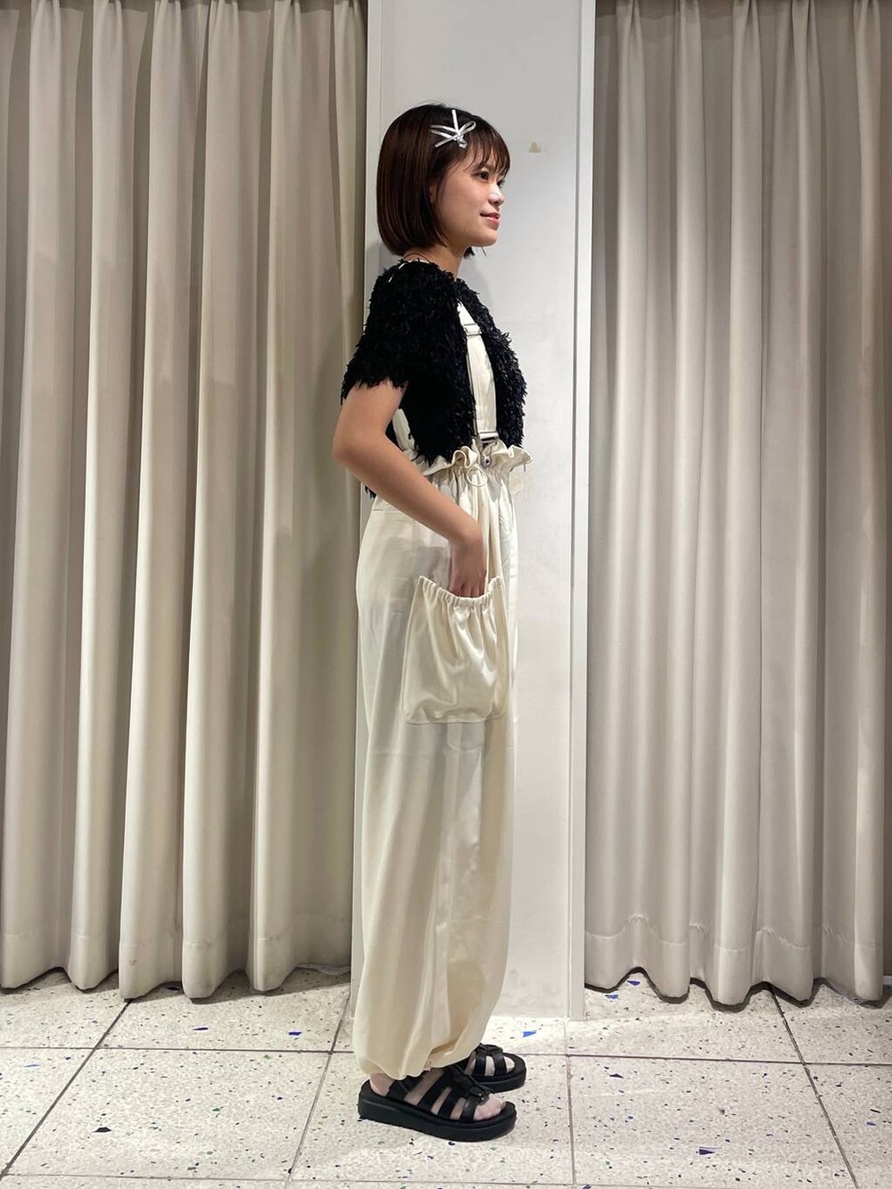 ホワイト系のワンピース、ブラック系のスニーカー、ブラック系のカーディガン/ボレロを着用したレディースの秋コーディネートの2枚目の写真