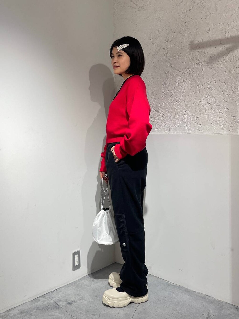 ブラック系のその他パンツ、ホワイト系のスニーカー、レッド系のニット/セーターを着用したレディースの秋コーディネートの2枚目の写真