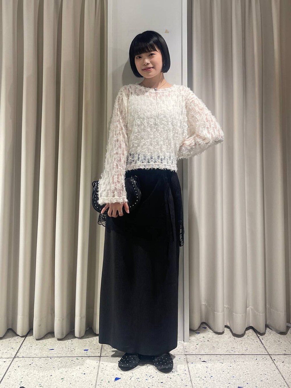 ブラック系のスカート、ブラック系のバレエシューズ、ブラック系のショルダーバッグを着用したレディースの秋コーディネートの5枚目の写真