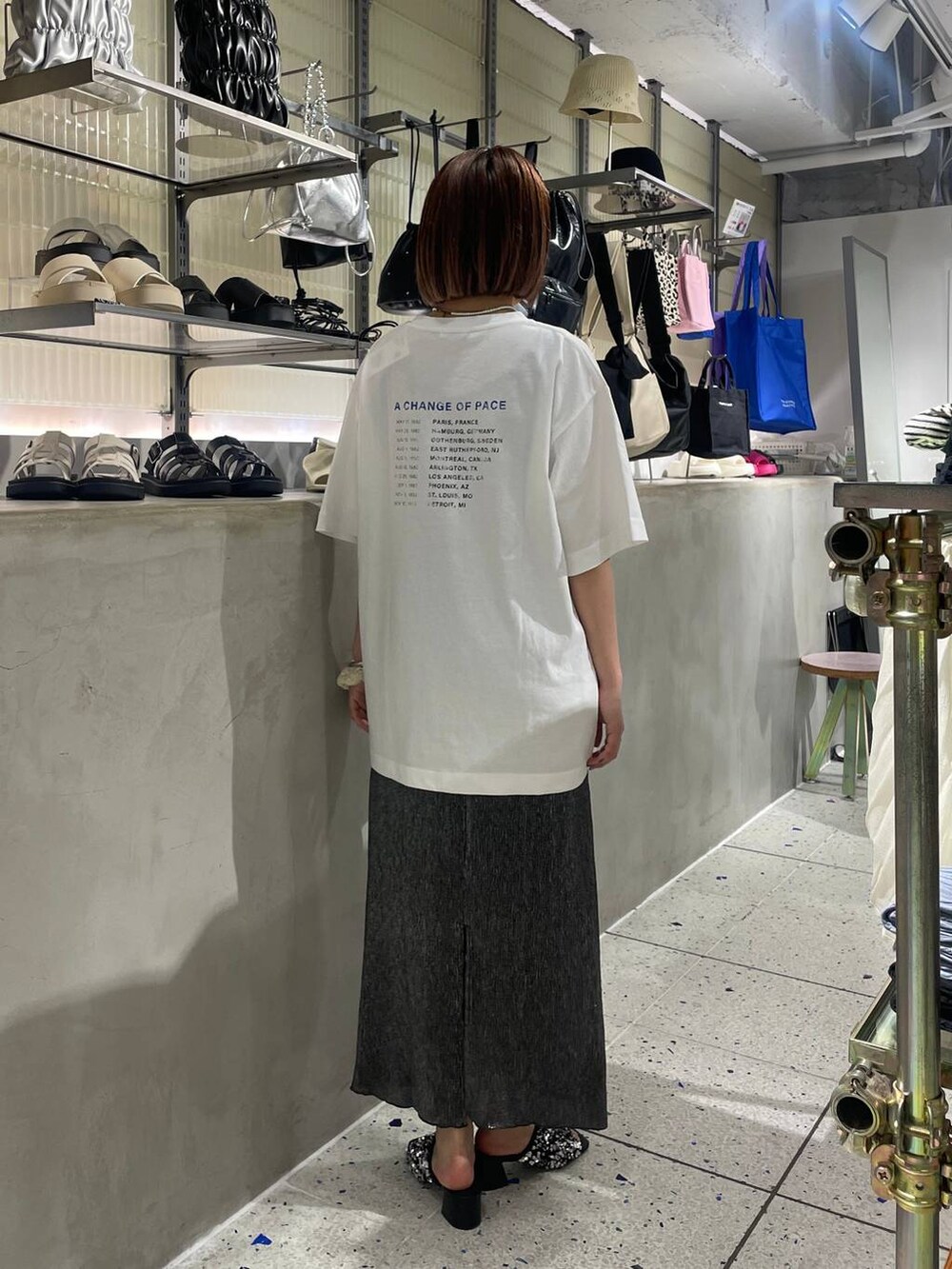 ホワイト系のTシャツ/カットソー、ブラック系のスカート、シルバー系のサンダルを着用したレディースの夏コーディネートの3枚目の写真
