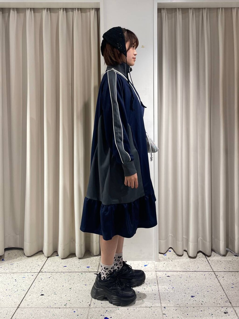 シルバー系のショルダーバッグ、ブラック系のスニーカー、ブルー系のワンピースを着用したレディースの夏コーディネートの2枚目の写真