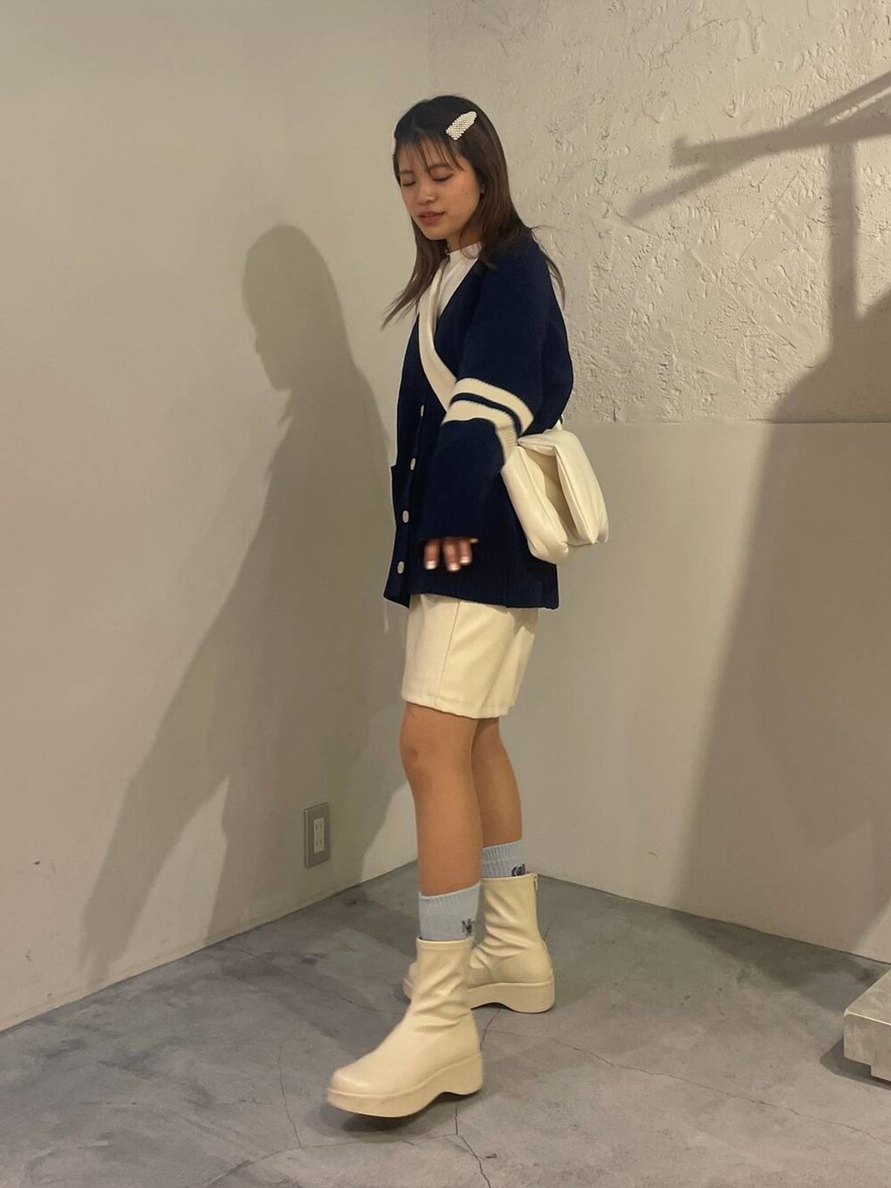 ホワイト系のブーツ、ホワイト系のTシャツ/カットソー、ホワイト系のショルダーバッグを着用したレディースの冬コーディネートの2枚目の写真