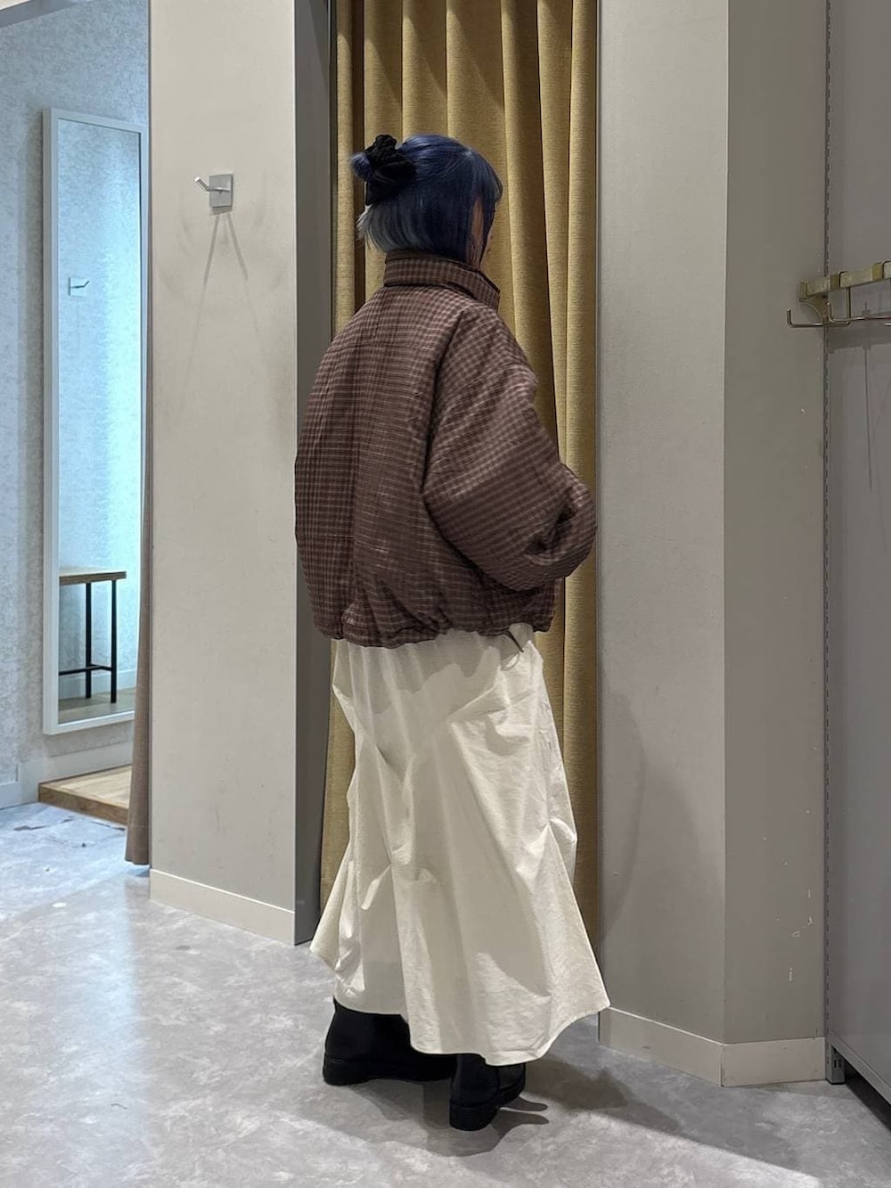 ブラック系のブーツ、ブラウン系のブルゾン、ホワイト系のスカートを着用したレディースの冬コーディネートの3枚目の写真