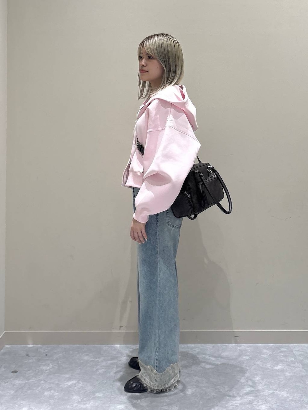 ピンク系のパーカー、ブルー系のデニムパンツ、ブラウン系のローファーを着用したレディースの春コーディネートの4枚目の写真