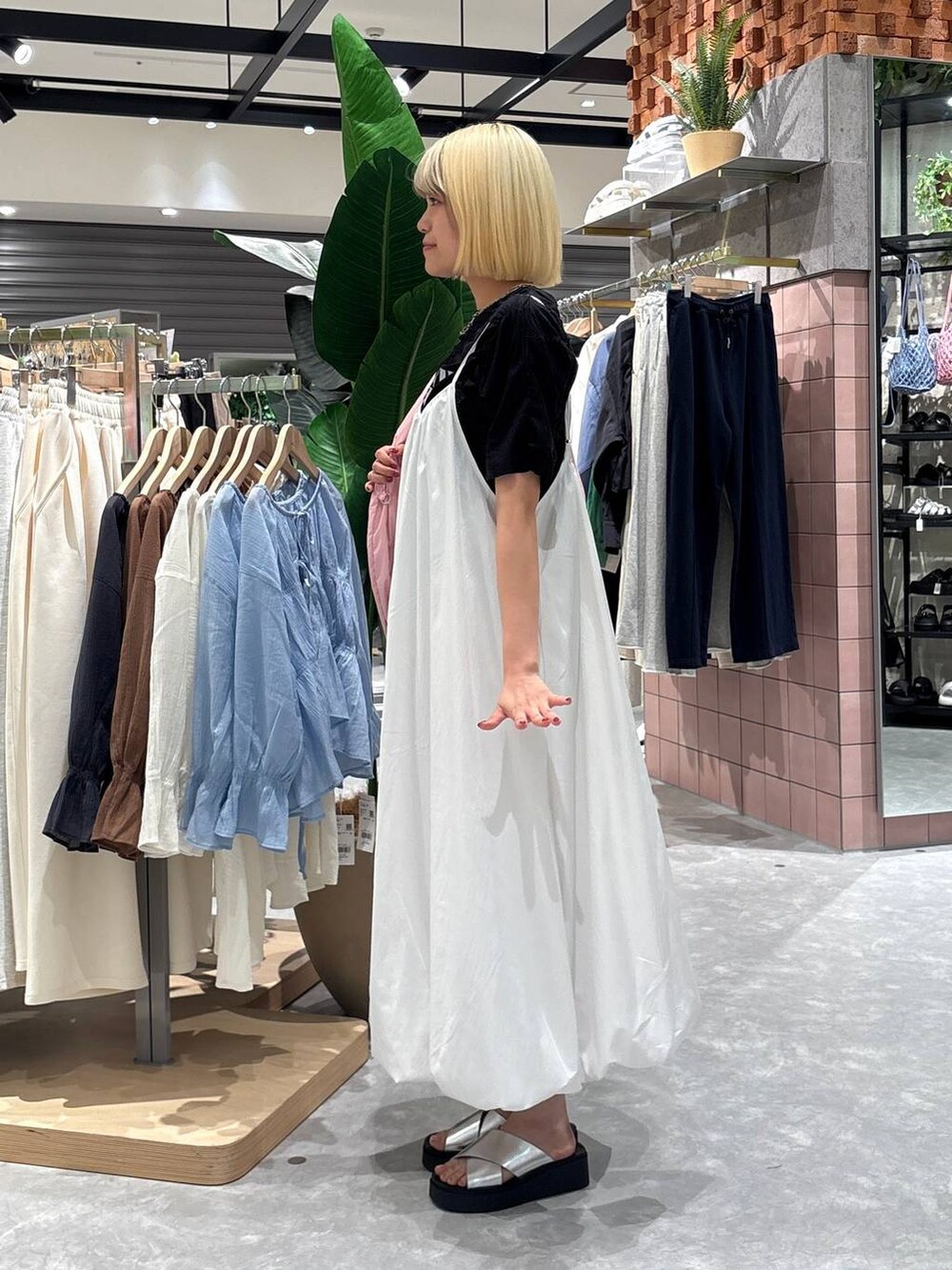 シルバー系のサンダル、ピンク系のトートバッグ、ホワイト系のワンピースを着用したレディースの夏コーディネートの3枚目の写真