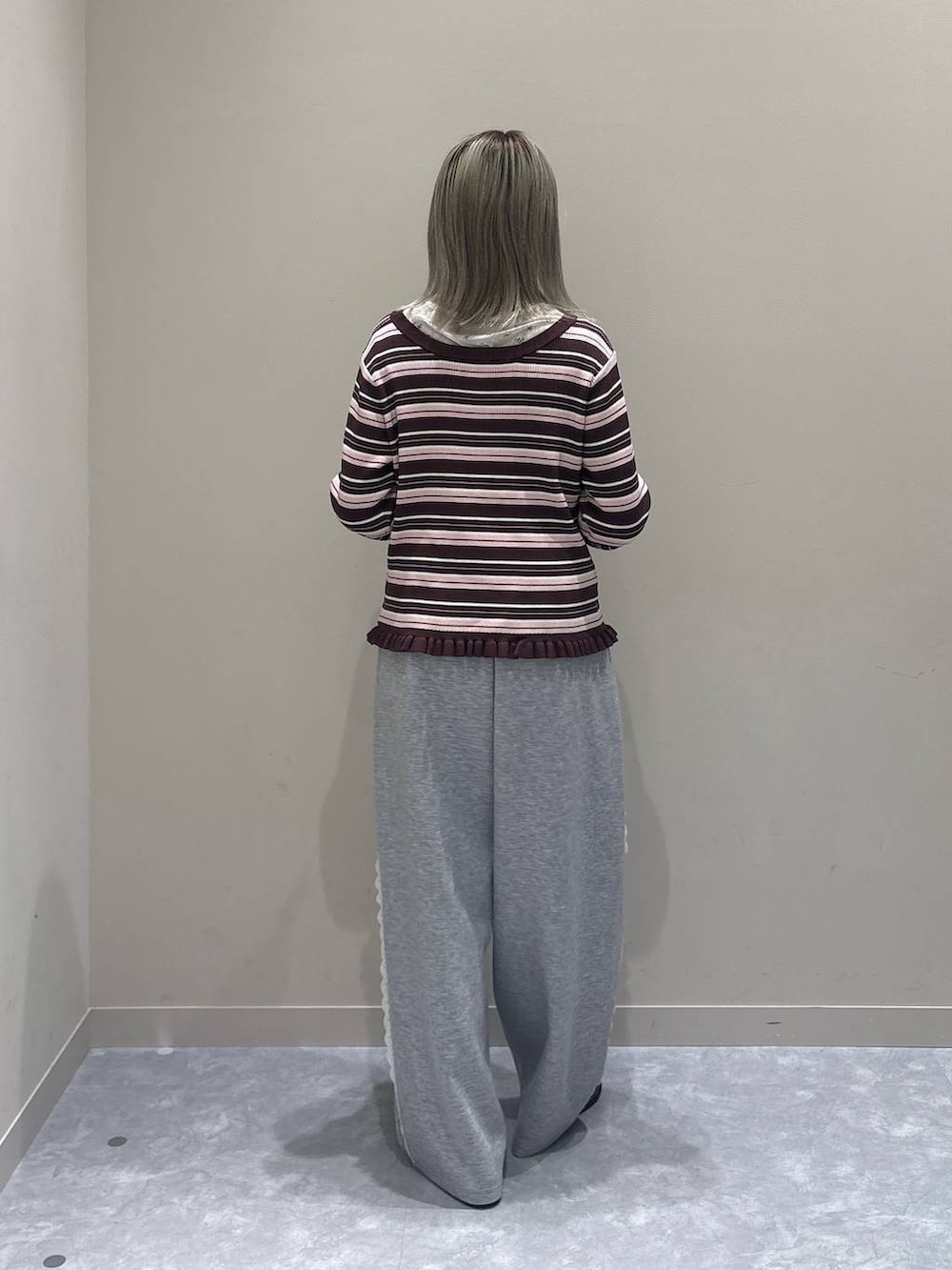 グレー系のスウェットパンツ、ホワイト系のTシャツ/カットソー、ブラウン系のニット/セーターを着用したレディースの冬コーディネートの3枚目の写真