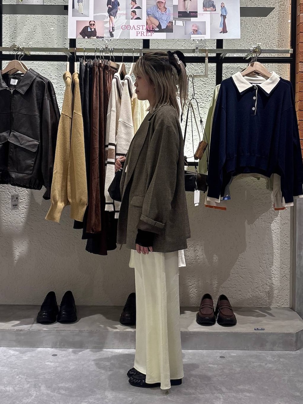 イエロー系のスカート、ブラウン系のテーラードジャケット、ブラック系のローファーを着用したレディースの春コーディネートの2枚目の写真