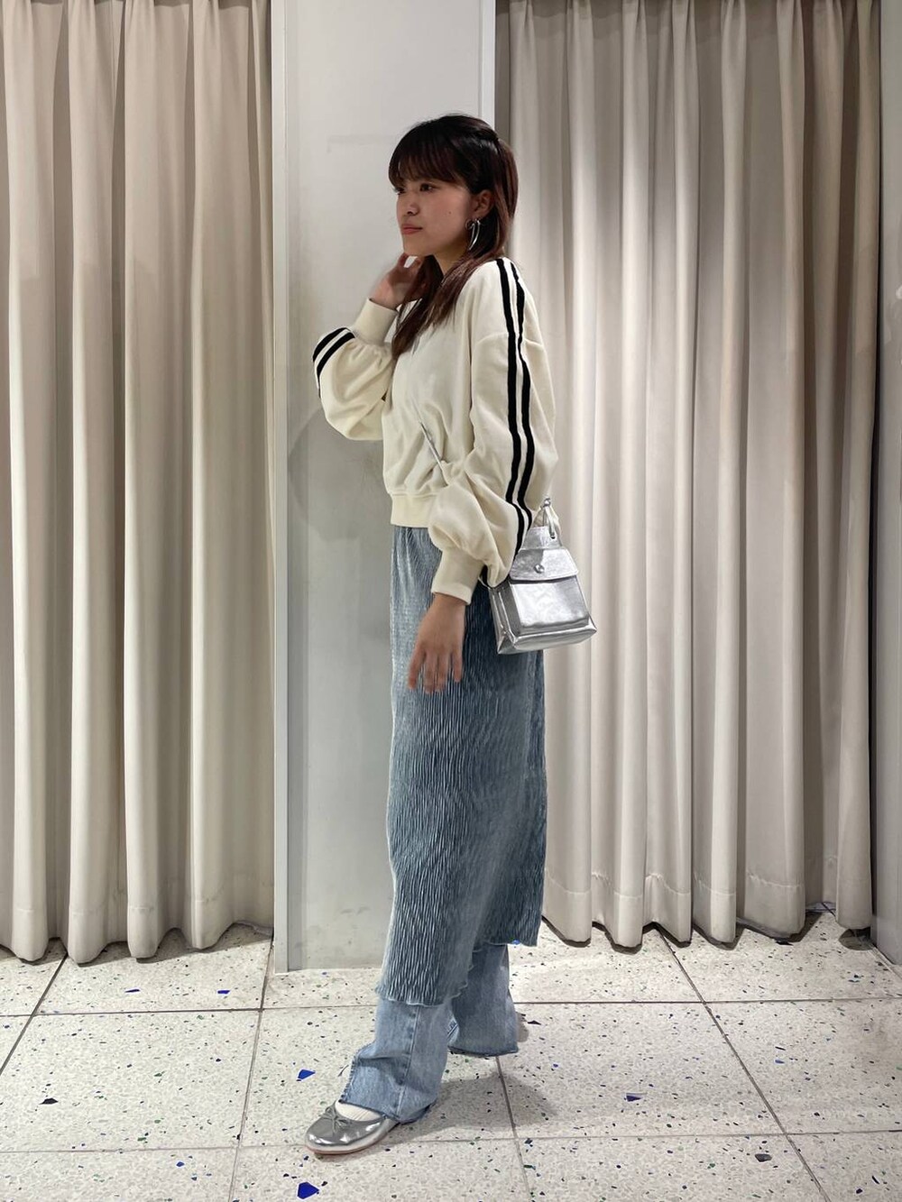 グレー系のバレエシューズ、ブルー系のデニムパンツ、ホワイト系のスウェットを着用したレディースの冬コーディネートの2枚目の写真