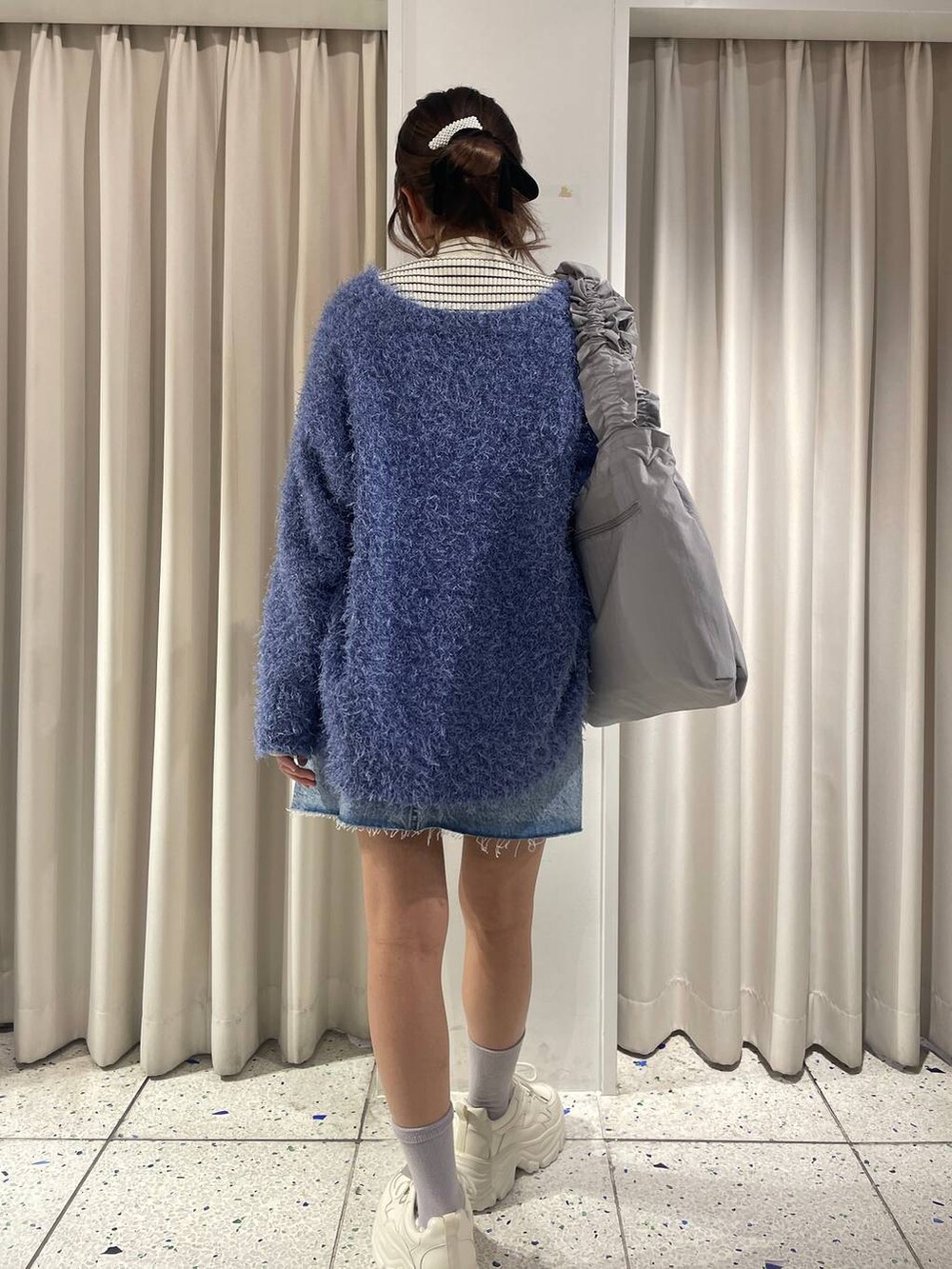 ホワイト系のカーディガン/ボレロ、グレー系のトートバッグ、ブルー系のスカートを着用したレディースの冬コーディネートの3枚目の写真